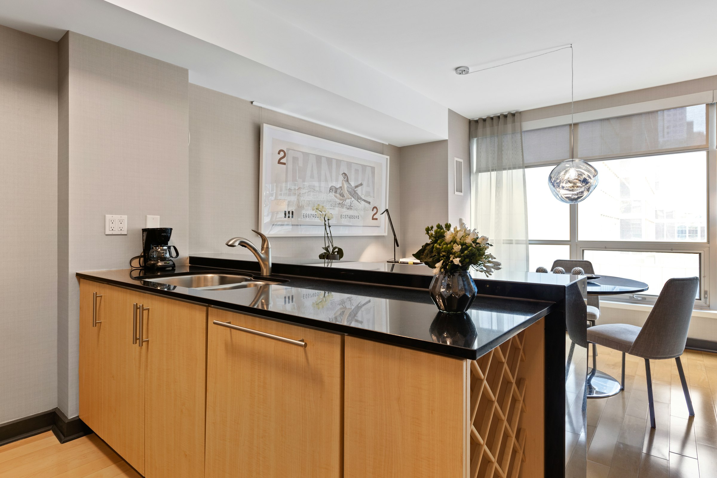 Furnished extended-stay kitchenette with wood cabinetry, dark countertop, and dining nook